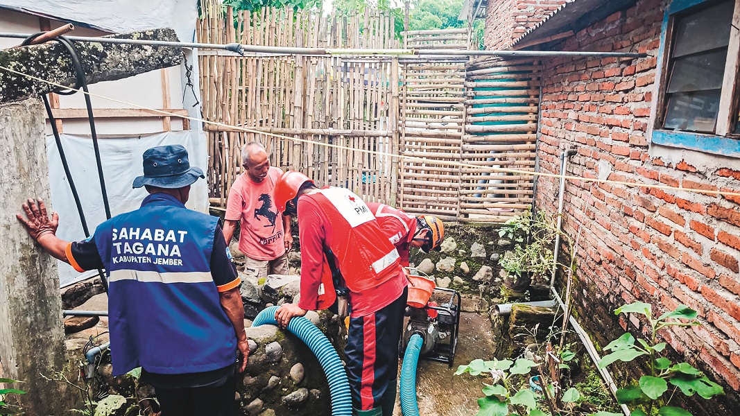 BANTU WARGA: Anggota PMI Jember melakukan normalisasi sumur warga yang terdampak banjir kawasan di Patrang, kemarin.