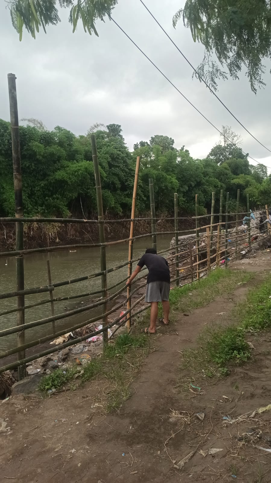 SWADAYA: Warga swadaya membangun pagar pembatas dari bambu di lokasi tanggul yang ambrol akibat banjir di perumahan Villa Indah Tegal Besar, kemarin.