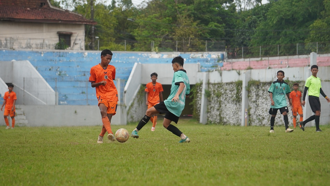 SENGIT: SSB Dharaka Jaguar Patrang (biru) mencoba memblok umpan SSB Pordes Kalisat U-14 (oranye) pada partai final Jatim Football League di Stadion Notohadinegoro, kemarin (29/12).