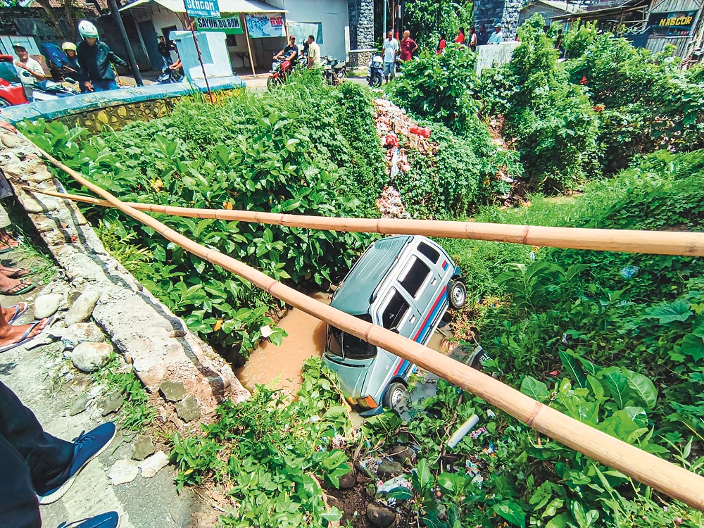 JADI TONTONAN: Mobil Suzuki Karimun terjun ke sungai, di depan Klinik Pratama, Dusun Ampo, Desa Dukuhmencek,&nbsp; Kecamatan Sukorambi, Senin (29/12).