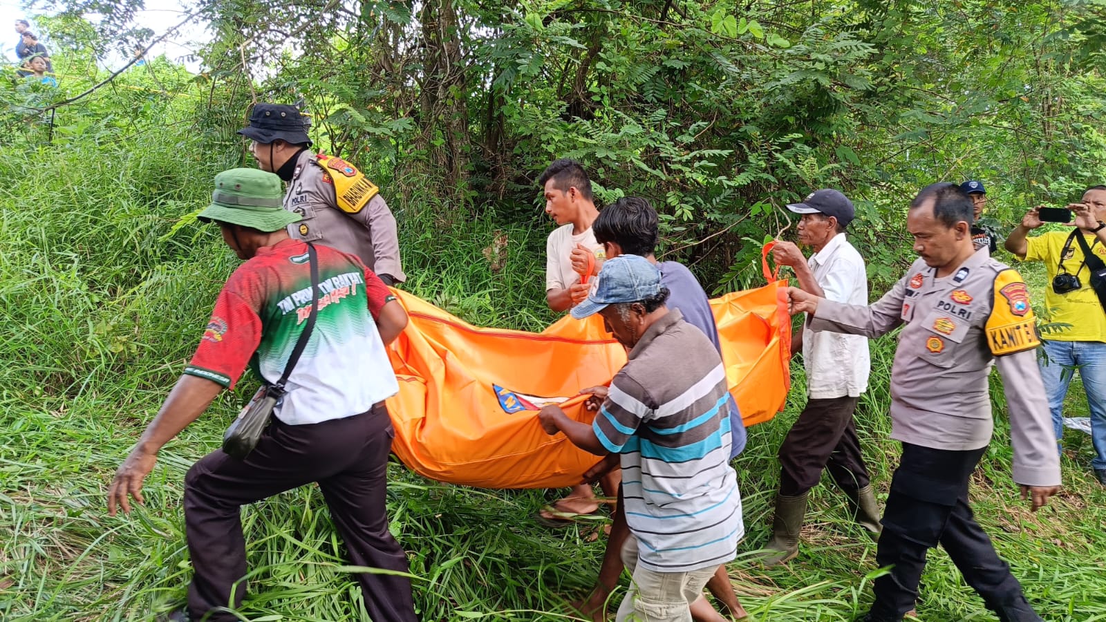 DIEVAKUASI: Petugas Polsek Bangsalsari bersama warga dan keluarga korban saat mengevakuasi korban pada Minggu (28/12).