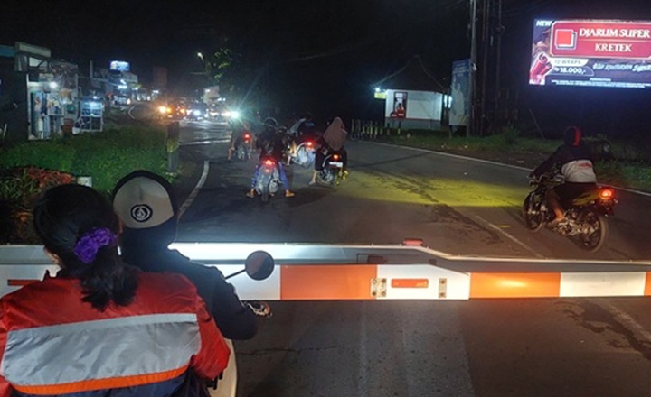 ABAIKAN KESELAMATAN: Beberapa pengendara yang masih menerobos pintu perlintasan KA di Arjasa walau petugas sudah menutup sebelum KA melintas.