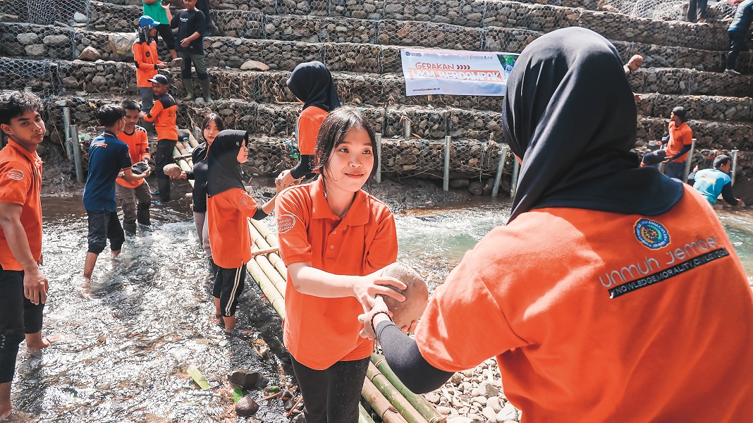 KOMPAK: Gabungan UKM Unmuh Jember gotong royong memasang bronjong di Jalan Imam Bonjol, Lingkungan Krajan RT 05 RW 04, Kelurahan Kaliwates, Kecamatan Kaliwates, Selasa (30/12).
