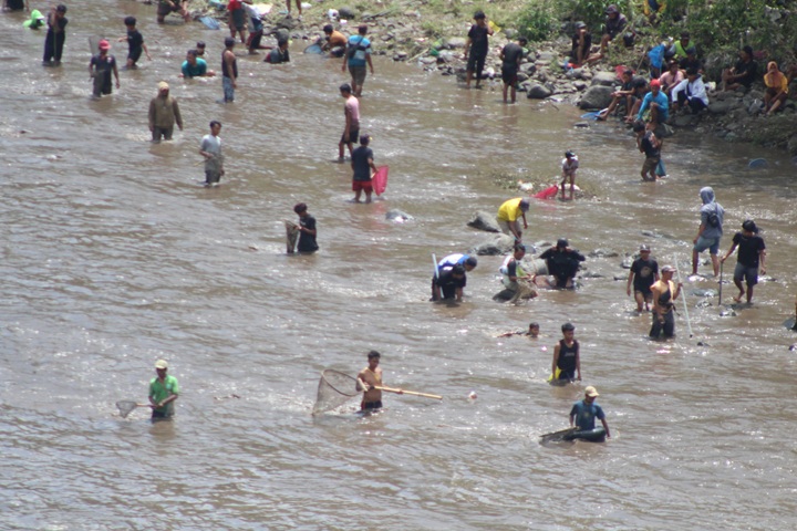 BERJIBAKU: Sejumlah pengunjung Asatan di Bendungan Sampean Baru mencari ikan ditengah tebalnya sedimentasi lumpur.
