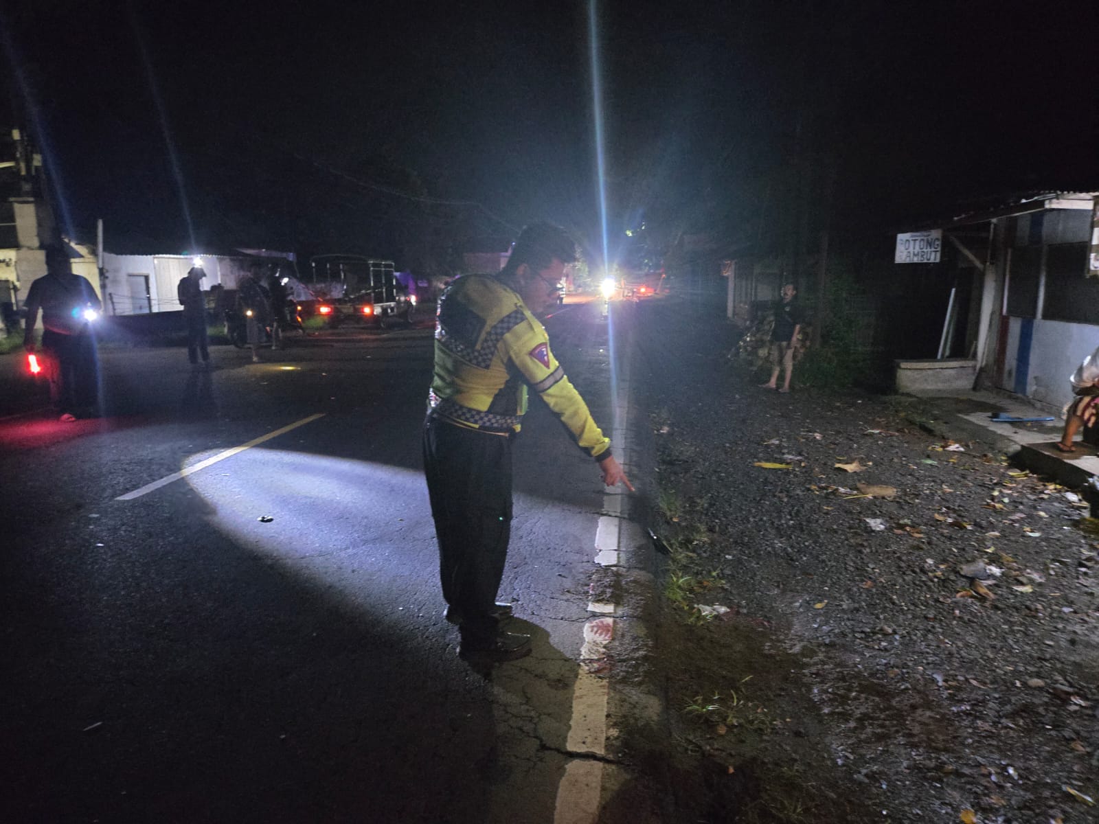 DATANGI LOKASI: Anggota Unit Laka Satlantas Polres Jember melakukan olah TKP kecelakaan lalu lintas di Jalan Raya Desa Gambirono, Kecamatan Bangsalsari, Kamis (1/1) pukul 02.00.