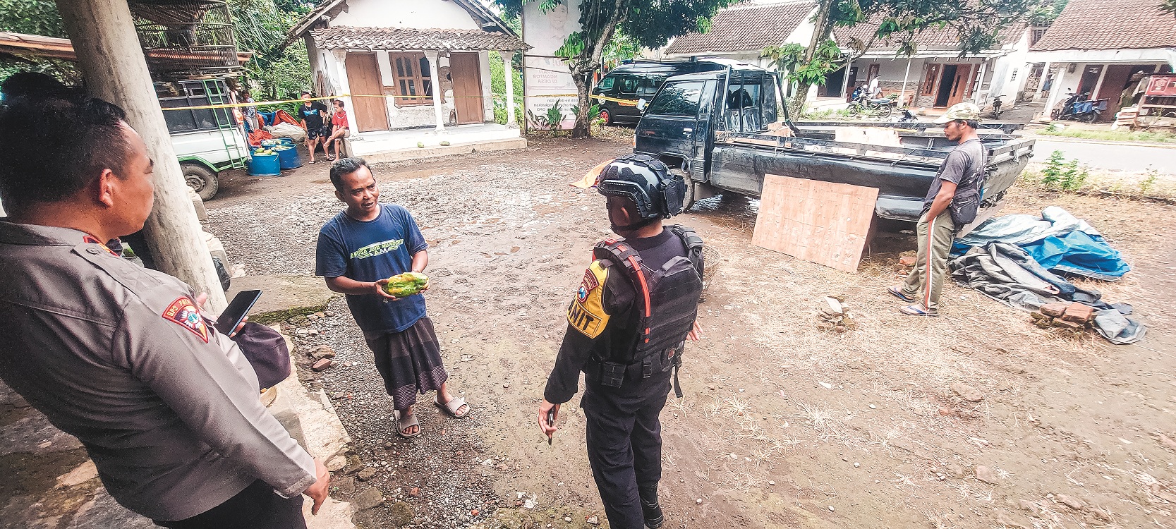 TUNJUKKAN PEPAYA DIISI KARBIT: Sugiono, korban yang juga pengepul buah pepaya menunjukkan cara memasukkan karbit ke dalam pepaya kepada tim Gegana Polda Jatim di lokasi ledakan mobil, kemarin.