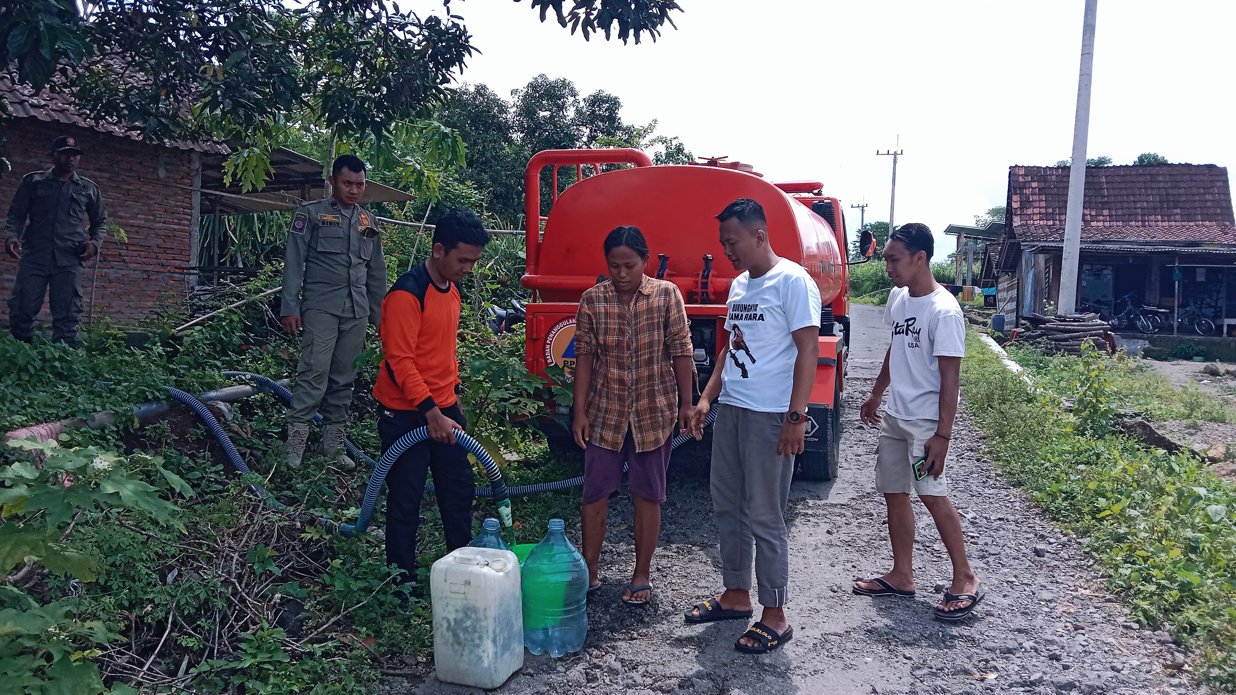 TERBATAS: Petugas BPBD menyalurkan air bersih di wadah yang sudah disiapkan warga Desa Klekean, Kecamatan Botolinggo.
