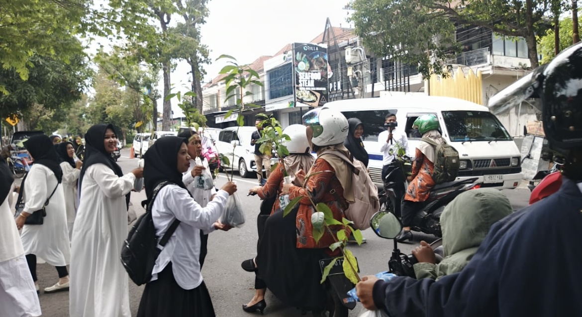 SUMRINGAH: Para pegawai KPH Perhutani Bondowoso memberikan bibit buah kepada pengendara yang melintas di depan kantor mereka, kemarin.(ILHAM WAHYUDI/RADAR IJEN)