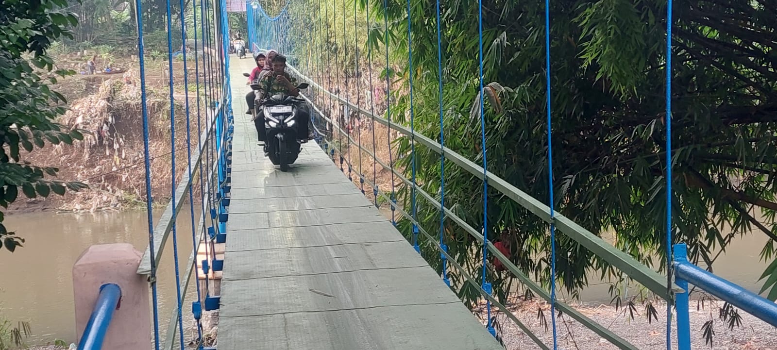 HARUS HATI HATI: Warga akhirnya bisa melewati kembali jembatan gantung, Desa Jubung, Kecamatan Sukorambi, Jember setelah dilakukan perbaikan akibat putus diterjang banjir pada Senin (15/12) lalu