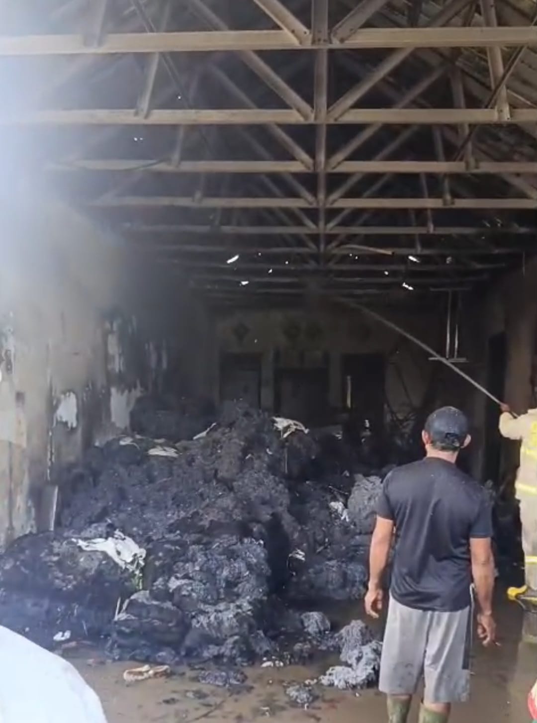 LUDES: Petugas damkar saat melakukan pendinginan di rumah milik Mustofa, warga Dusun Krajan, Desa Glundengan, Kecamatan Wuluhan pada Sabtu (20/1) siang.