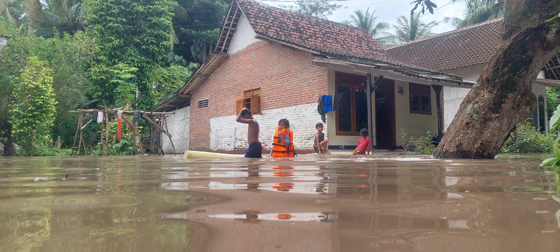 GENANGAN AIR: Air luapan dari Kali Clutak, Dusun Kepel, Desa Lojejer, Kecamatan Wuluhan, yang menggenangi rumah warga dijadikan tempat bermain, kemarin.