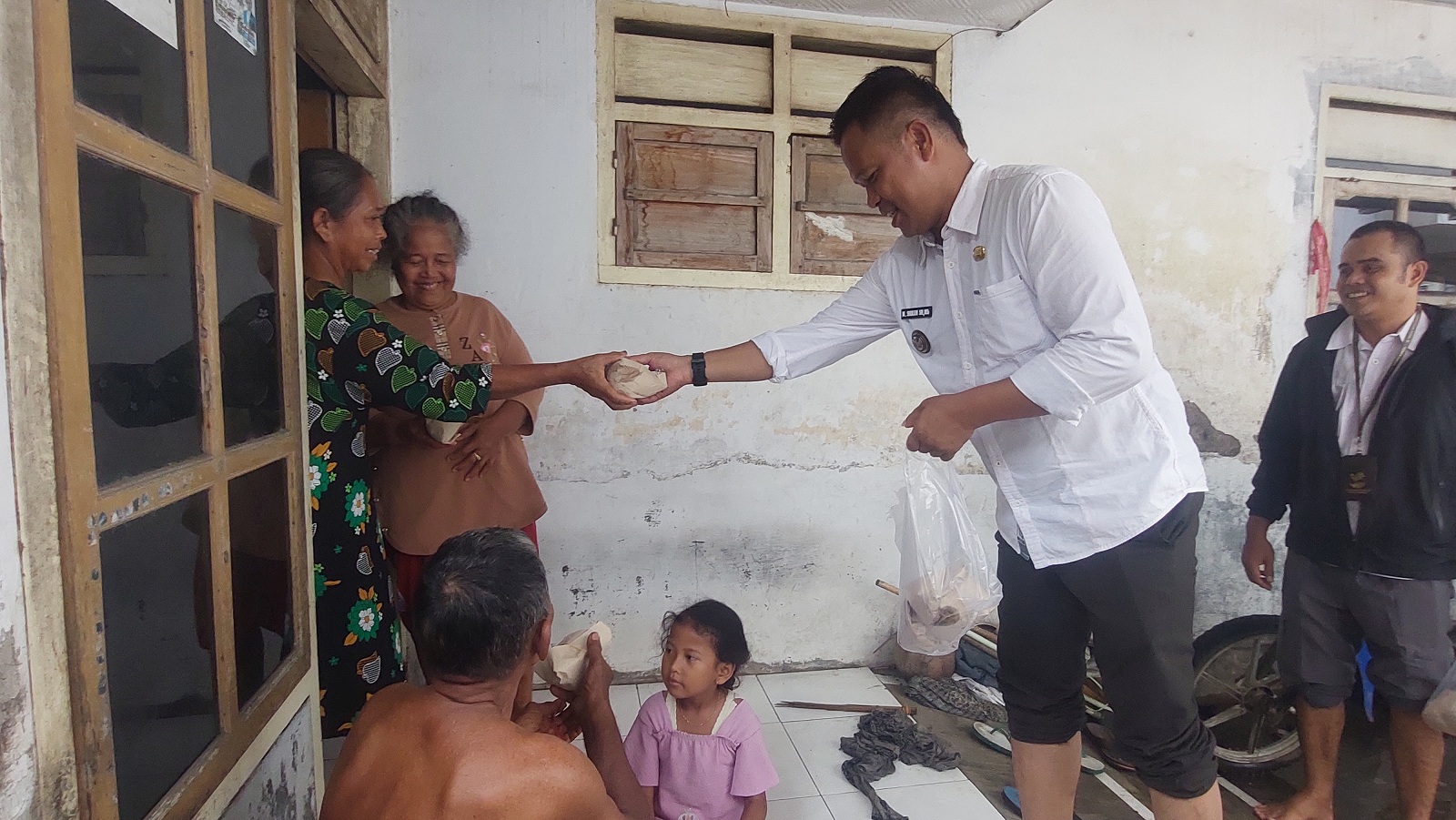 SERAHKAN NASI SIAP SAJI: Mohammad Soleh, Kepala Desa Lojejer, Kecamatan Wuluhan, bersama Babinsa dan perangkat desa menyerahkan nasi siap saji kepada warga yang terdampak banjir, Rabu (14/1).