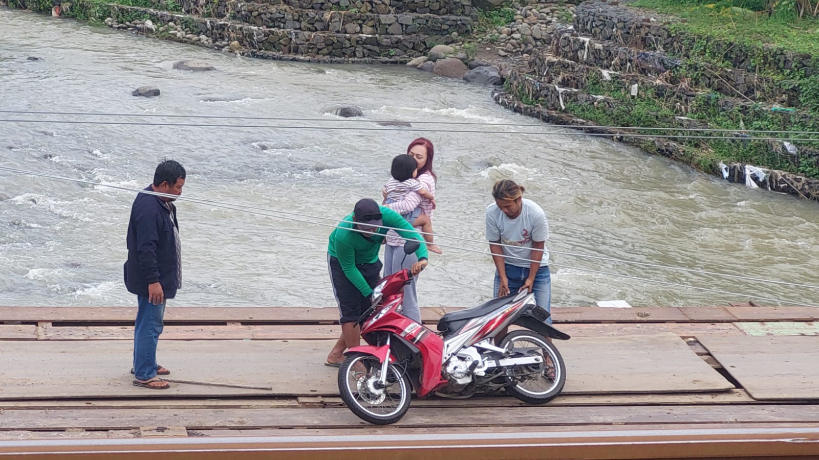 NYARIS CELAKA: Seorang ibu bersama anaknya yang masih kecil harus ditolong pekerja proyek jembatan kereta api (ka) di Dusun Krajan Selatan, Desa Patemon, Kecamatan Pakusari terjatuh saat melewati jemb