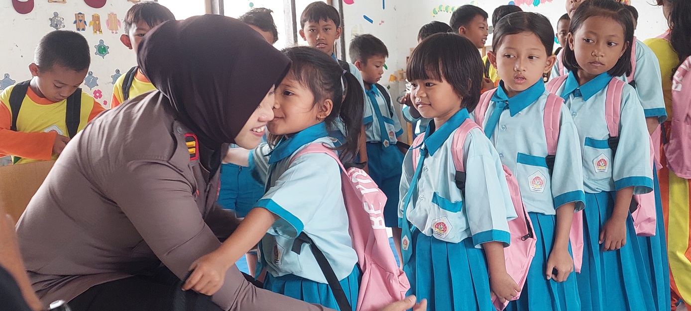 SENANG: Siswa SDN Sumber Ketempa 04 memeluk Kapolsek Kalisat Iptu Ika Mufid Dati setelah mendapatkan tas, alat tulis, dan bola.