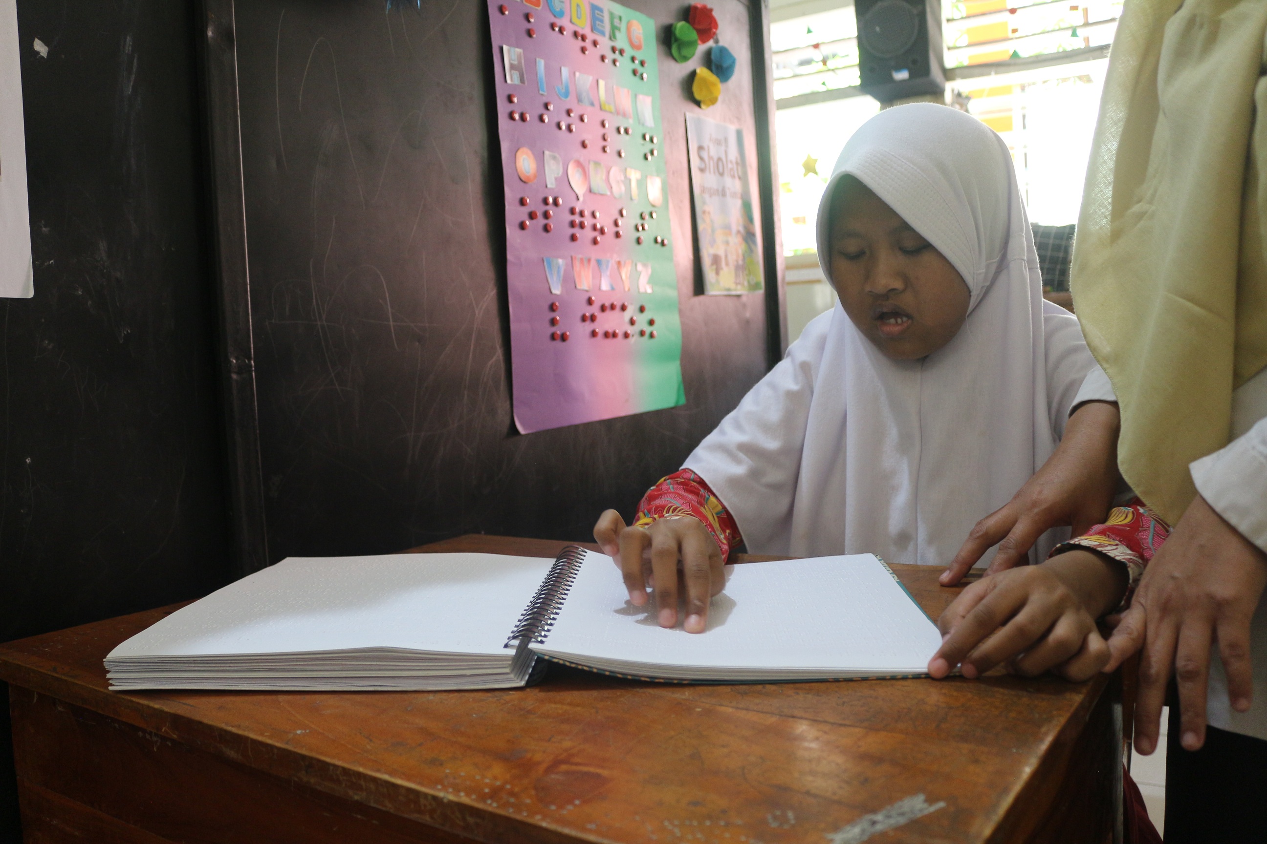 TELITI: Seorang penyandang tuna netra Maulidia Zahira membaca Alquran secara mandiri dan lancar dengan bantuan Alquran braille, kemarin.