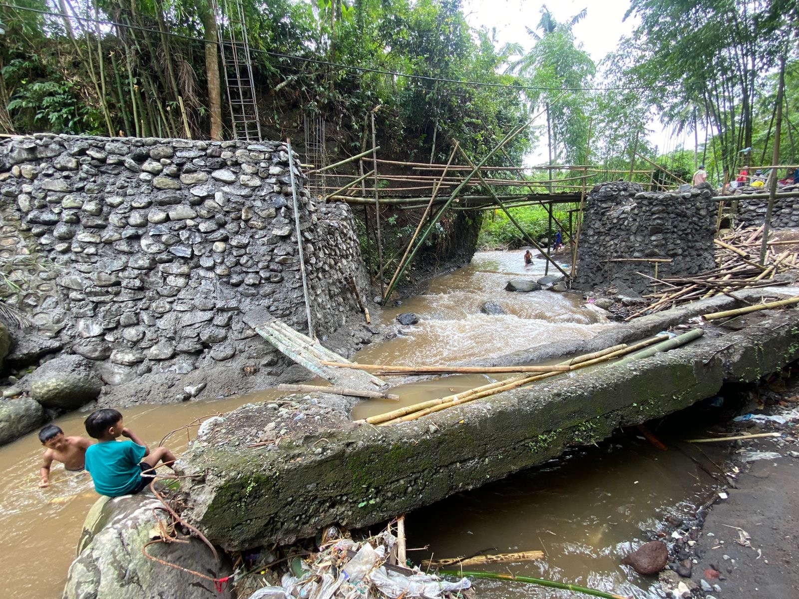 RUSAK PARAH: Sejumlah anak-anak melihat Warga Desa /Kecamatan Tlogosari bergotong royong membuat jembatan yang Rusak sejak 2024 lalu.(ILHAM WAHYUDI/RADAR IJEN)