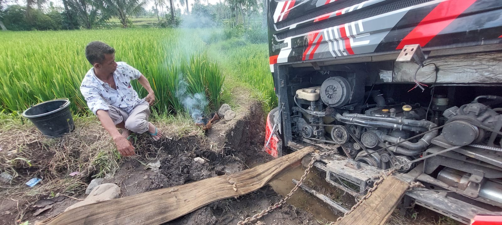 RITUAL DI LOKASI: Sopir bernama Hari Mulyono, 55, warga Kecematan Gucialit, Kabupaten Lumajang melakukan ritual dengan membakar kemenyan disekitar bus sebelum proses evakuasi.