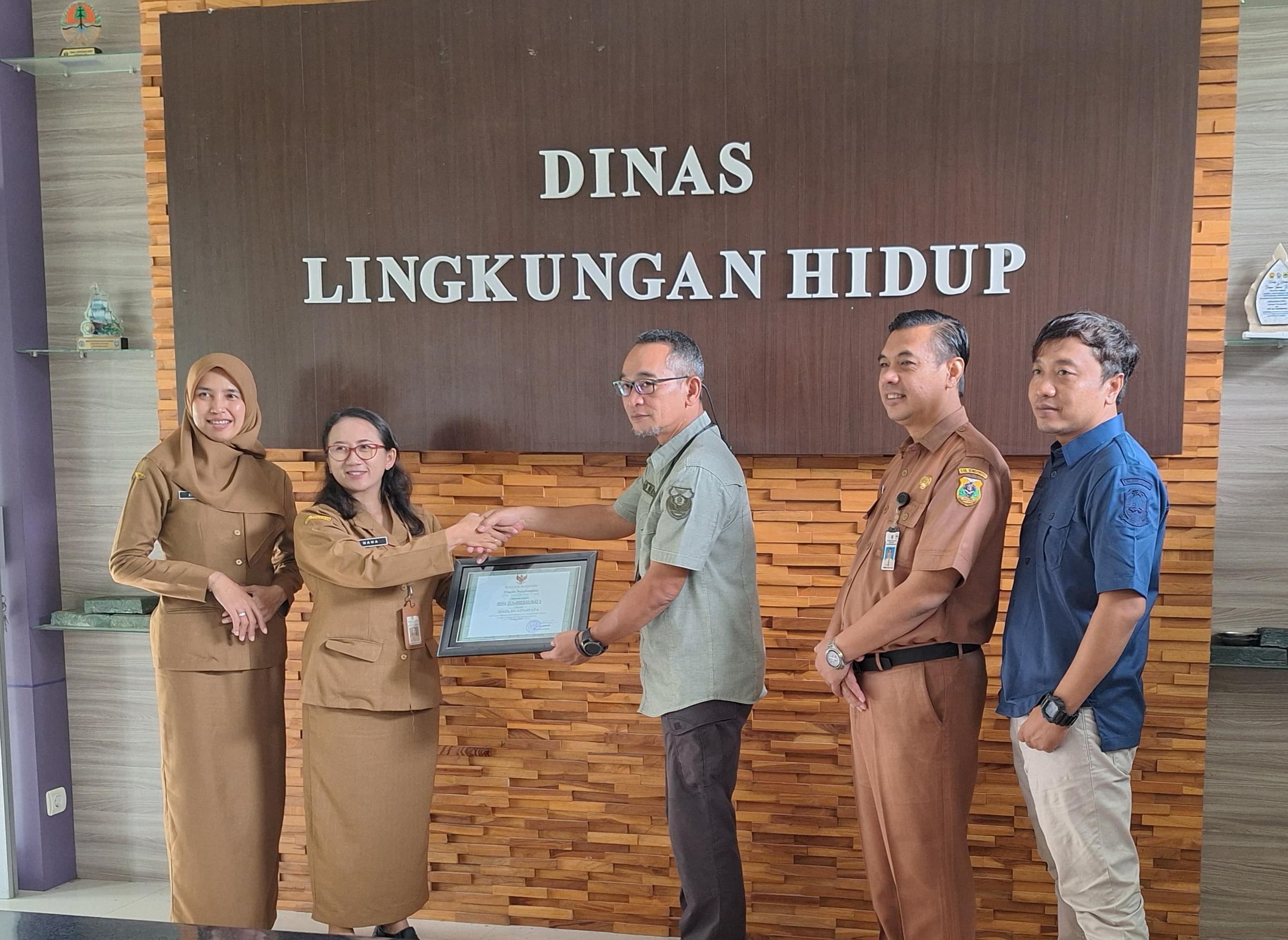 Plt Kepala DLH Bondowoso, Aris Agung Sungkowo menyerahkan sertifikat sekolah Adiwiyata, kemarin