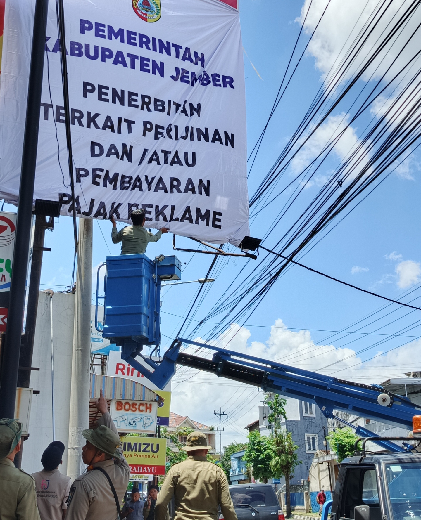 Petugas gabungan saat melakukan penertiban reklame kadaluarsa di sepanjang kawasan Segitiga Emas Jember Kota, Selasa (3/2/2026). (Maulana/JPRJ)