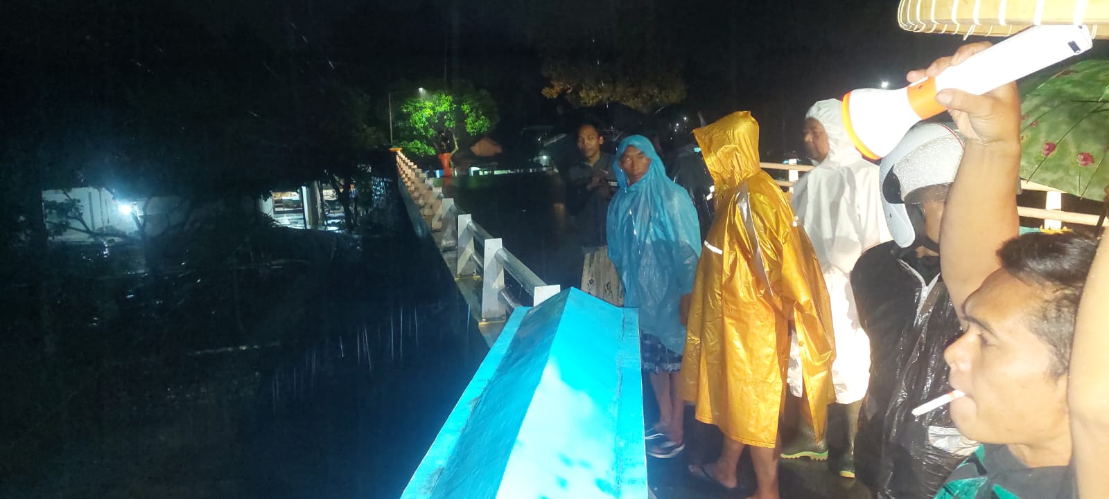 WARGA MELIHAT DEBIT AIR: Warga sekitar dan perangkat desa Pakis saat melihat kondisi air sungai Petung yang terus membesar. (JUMAI/RJ)