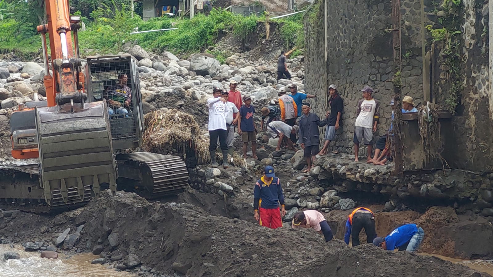 GUNAKAN ALAT BERAT: Alat berat milik Dinas PU BMSDA Jember bersama tim teknisi dibantu petani saat memasang bronjong yang hancur diterjang banjir. (JUMAI/RJ)