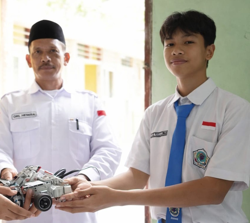 KEREN: Ahmad Yusril Astaghina, Siswa kelas XI Sains MAN 3 Jember (kanan) bersama gurunya memamerkan karya robotik.