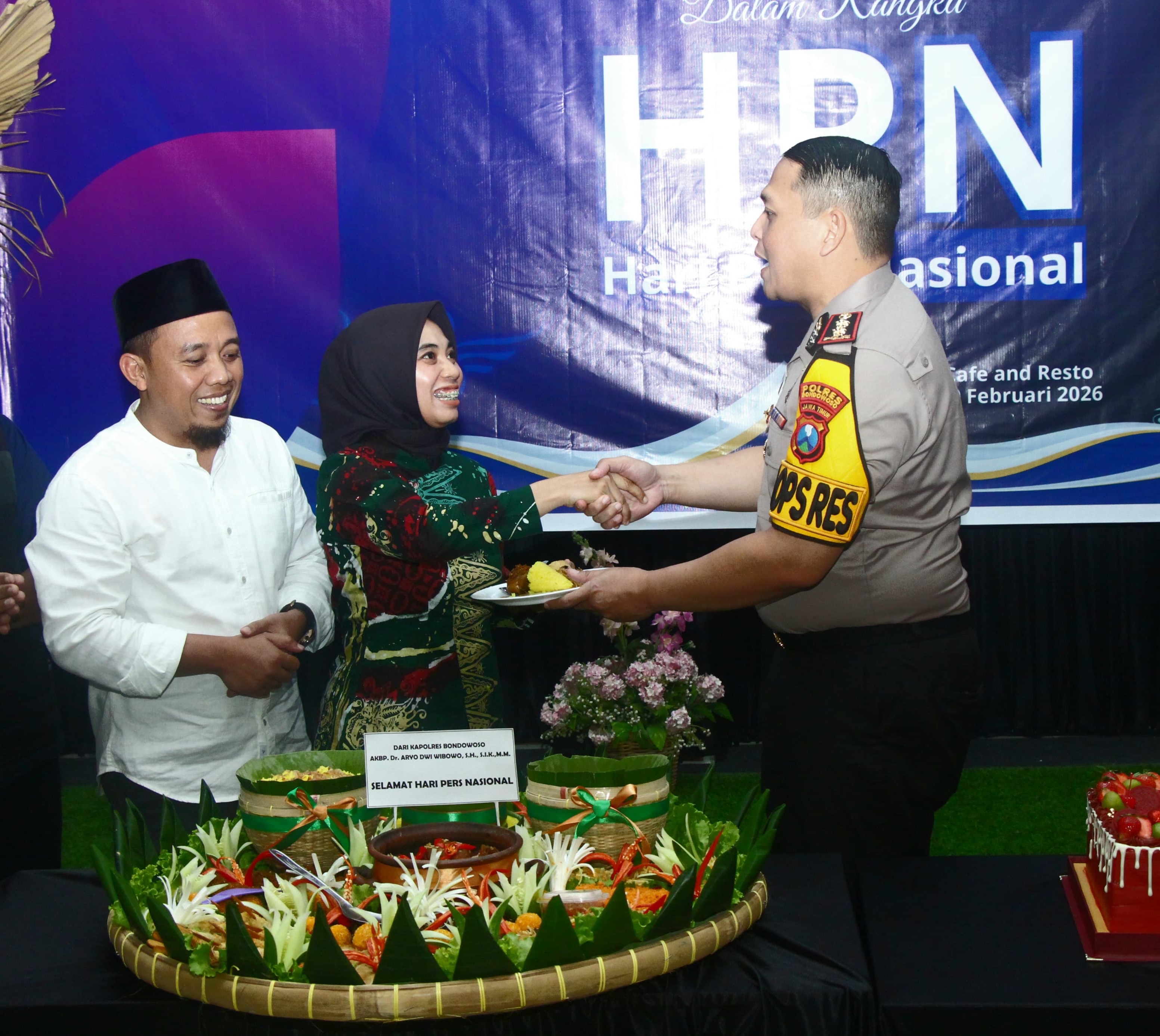 KHIDMAT: Kapolres Bondowoso, AKBP Dr. Aryo Dwi Wibowo memberikan potongan tumpeng pertama kepada Ketua PWI Bondowoso, Sinca Ari Pengestu. Kemarin (9/2)