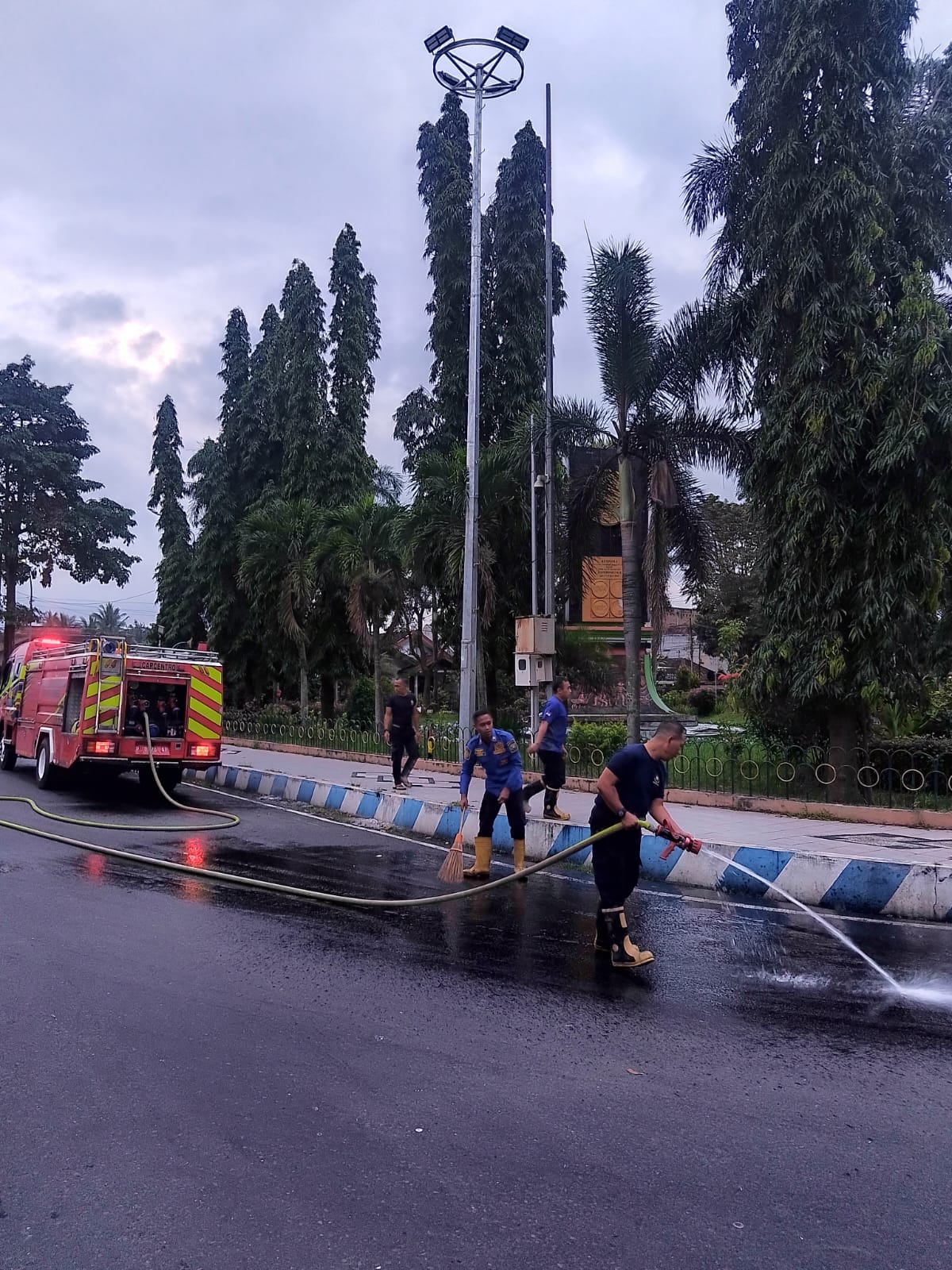 DIBERSIHKAN: petugas saat mrmbersihkan tumpahan solar yang mengganggu pengendara di bunderan Nangkaan beberapa waktu lalu.