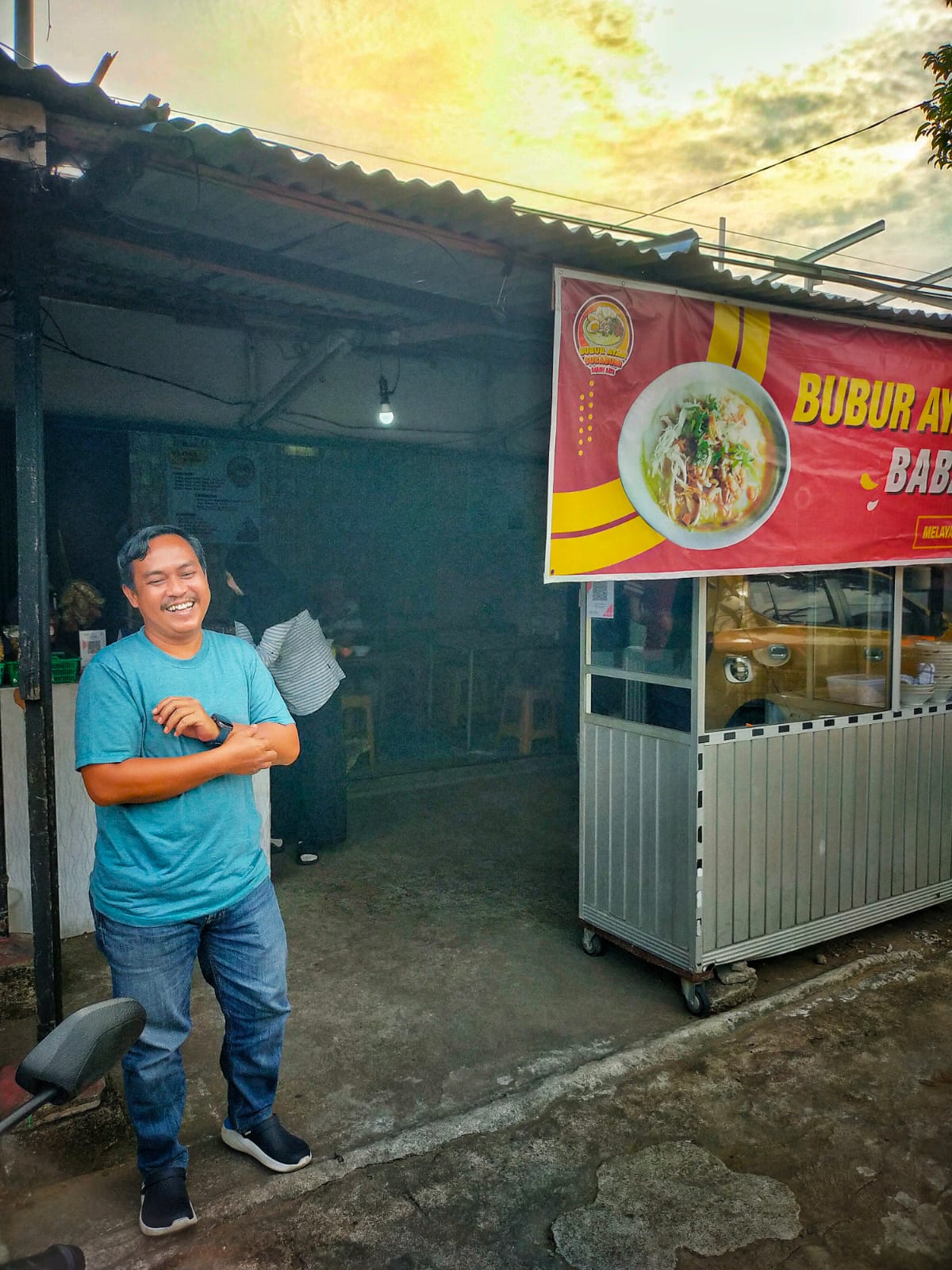 Teks foto; Azis berdiri di depan kiosnya