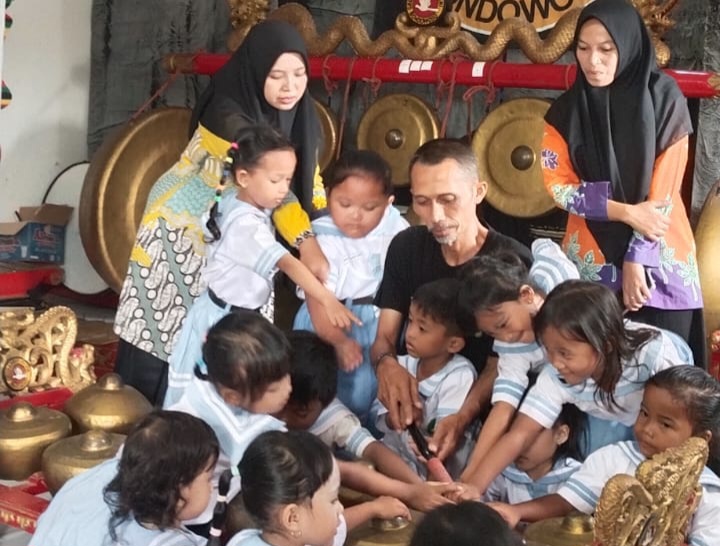 TELATEN: Koordinator Gas Bondowoso mengajarkan cara bermain gamelan kepala siswa yang datang ke tempatnya.