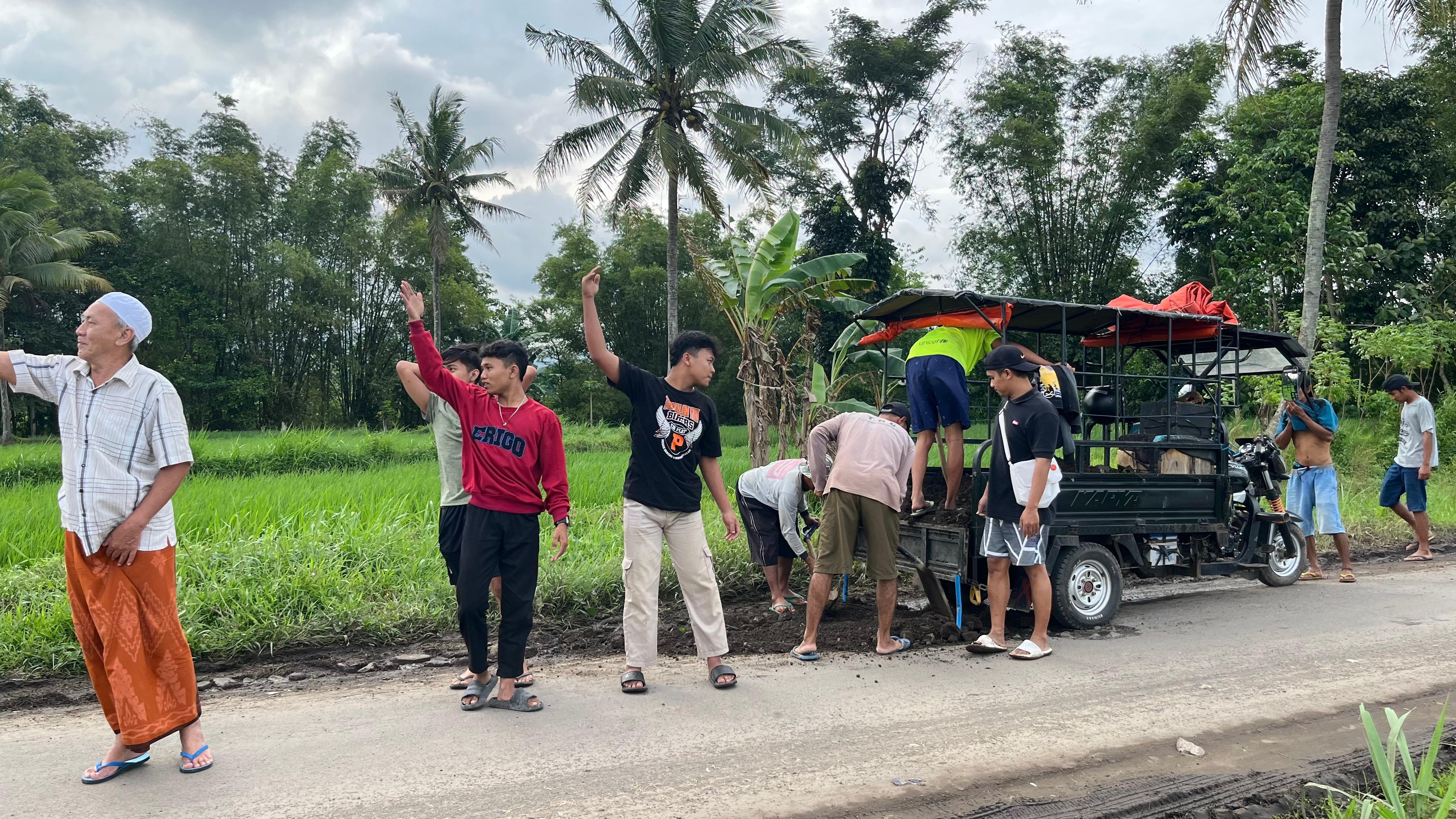 DITAMBAL:Sejumlah pemuda saat menambal titik jalan yang berlubang,  