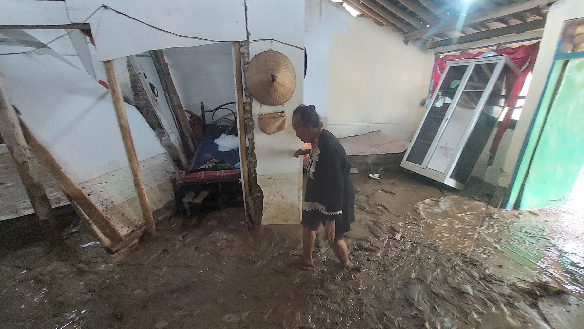TERSISA LUMPUR: Sumiyah, 67 warga Dusun Krajan, Desa Gugut, Kecamatan Rambipuji mengecek kondisi rumahnya yang rusak parah akibat banjir dari luapan Sungai Dinoyo. 