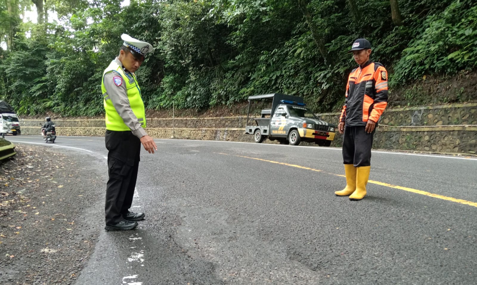 CEK JALAN: Anggota Polsek Silo menemukan titik jalan aspal rusak di Jalur Gumitir, Desa Sidomulyo, Kecamatan Silo, kemarin (4/3). (JUMAI/RJ)