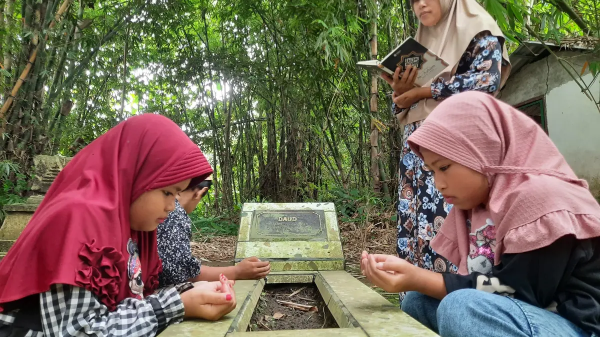 FAQIH HUMAINI/RADAR IJEN
KHUSYUK: Orang tua saat mengajarkan anak untuk berdoa kepada yang sudah meninggal