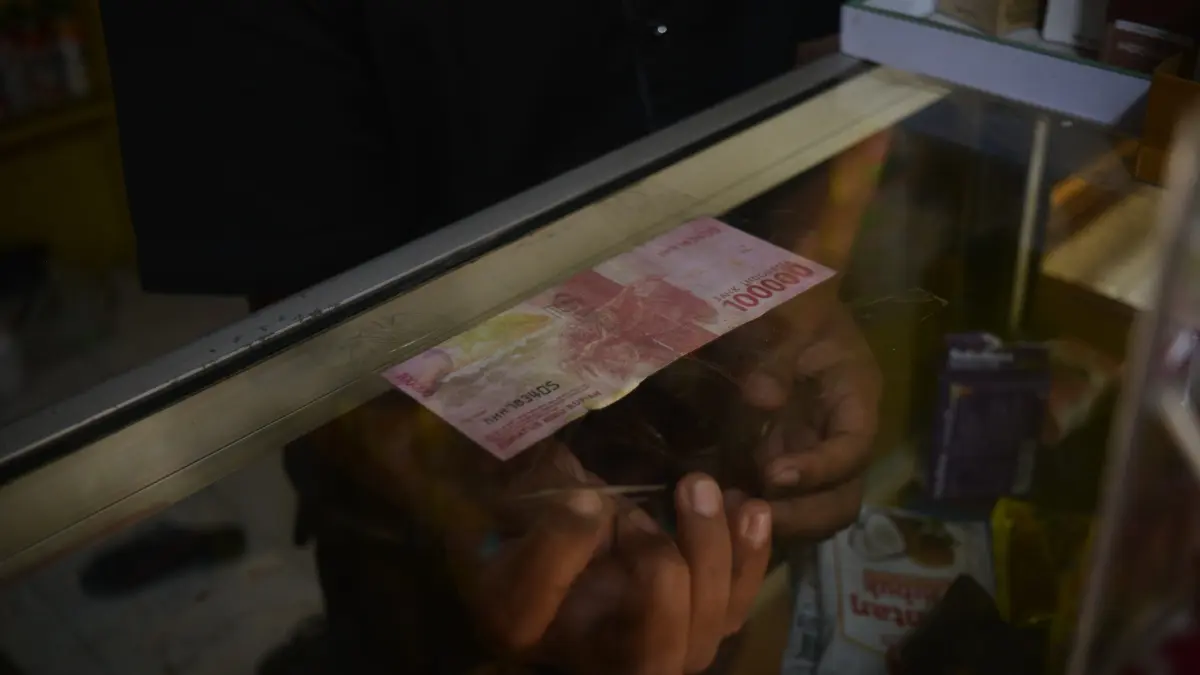 ANTISIPASI: Penjaga toko klontong Jalan Sumatera, Kecamatan Sumbersari, Faizal Efendi memasang uang palsu pecahan 100 ribu di etalase. (M ADHI SURYA/RADAR JEMBER)