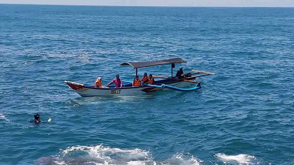 TERUS DISISIR: Pencarian korban hilang di Pantai Papuma terus dilakukan oleh tim SAR gabungan bersama keluarga korban menggunakan perahu dan jukung nelayan. (JUMAI/RADAR JEMBER)