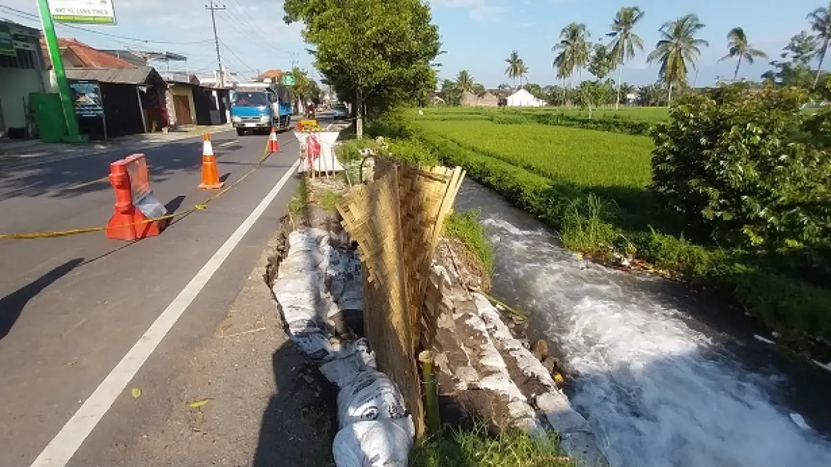 AMBROL KESALURAN: Plengsengan Jalan Nasional Jember - Banyuwangi yang ambrol kesaluran di Desa Tegalrejo, Kecamatan Mayang pada Sabtu (28/3) lalu dipasang sak berisi pasir. (Jumai/Radar Jember)