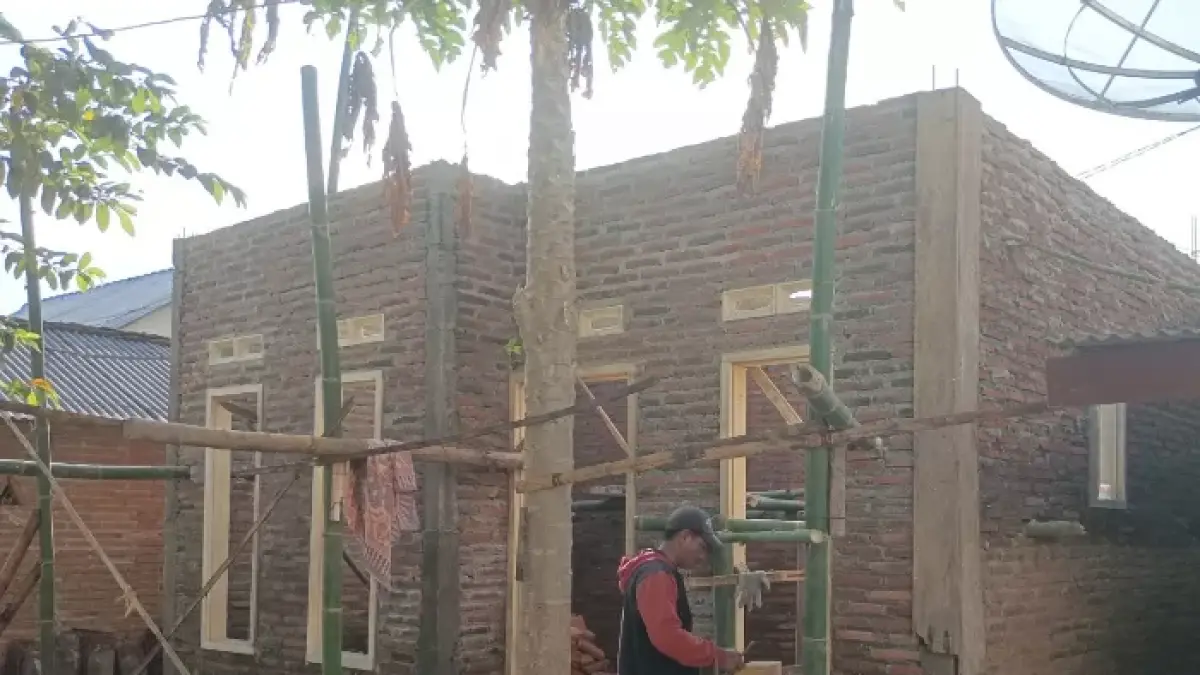 DIGARAP: Salah seorang pekerja memperbaiki rumah warga yang tak layak huni.