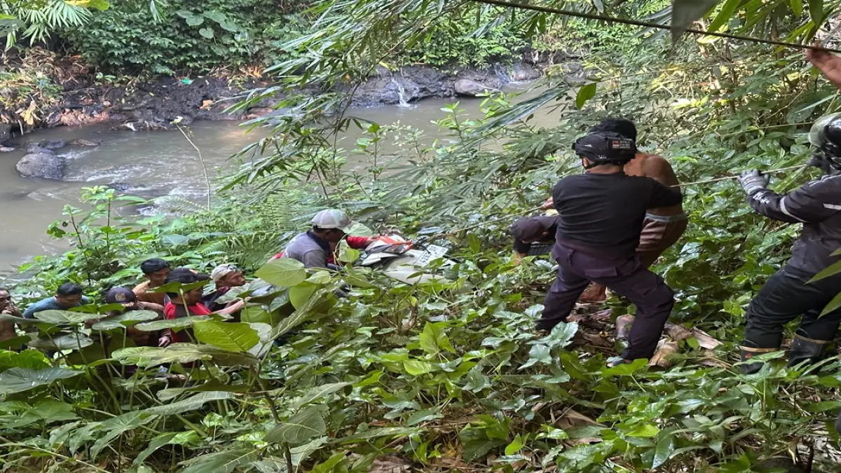 DIANGKUT: Petugas dan warga saat menggotong motor terjun ke sungai, kemarin (4/4).