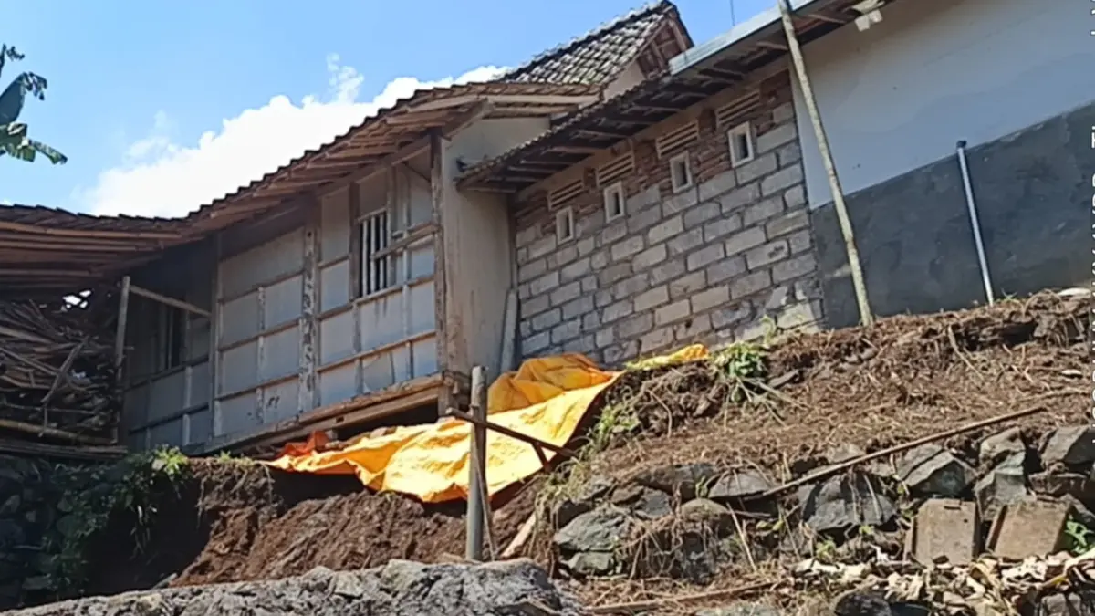 DIPASANG TERPAL: Petugas BPBD Jember memasang terpal di lokasi longsoran pondasi rumah warga di Desa Pringgowirawan, Kecamatan Sumberbaru, Senin (13/4). (BPBD JEMBER)
