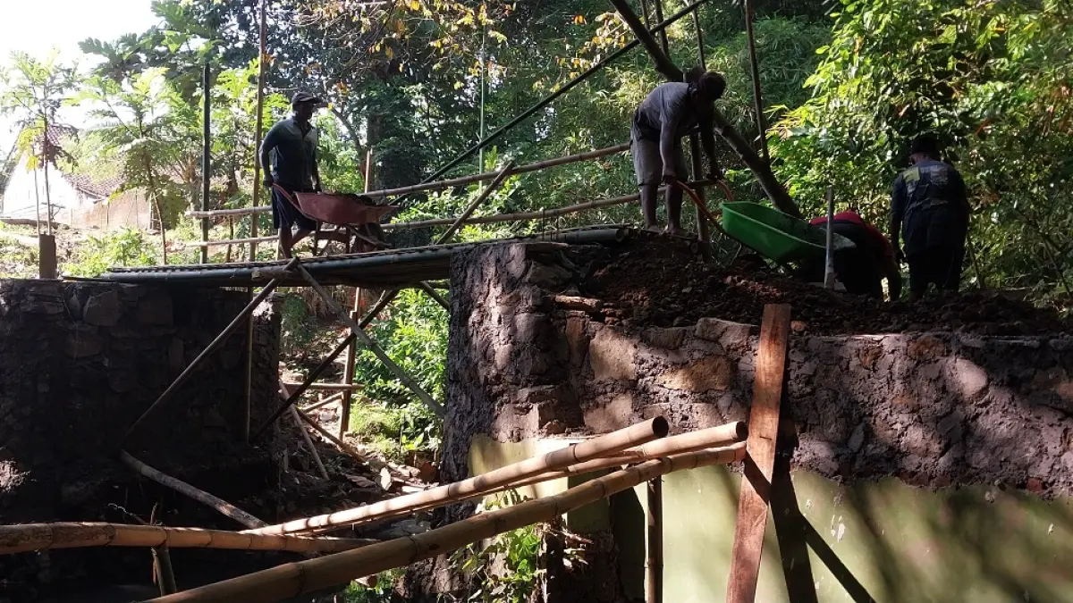 KOMPAK: Warga Dusun Jatirejo, Desa Cangkring bersama warga Dusun Wetan Gunung, Desa Wonojati, Kecamatan Jenggawah, bergotong-royong memperbaiki jembatan yang putus akibat banjir. (JUMAI/RADAR JEMBER)