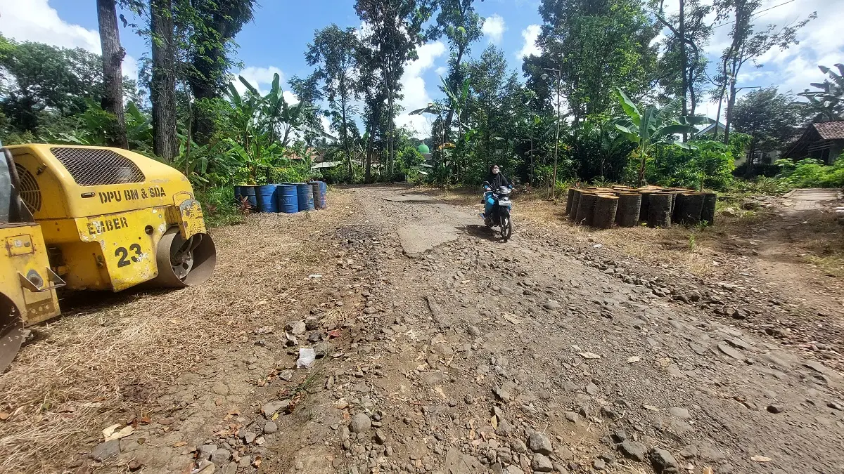 RUSAK:&nbsp;Pengguna jalan harus melewati jalan aspal yang tinggal batuan makadam di Desa Badean. (JUMAI/RADAR JEMBER)