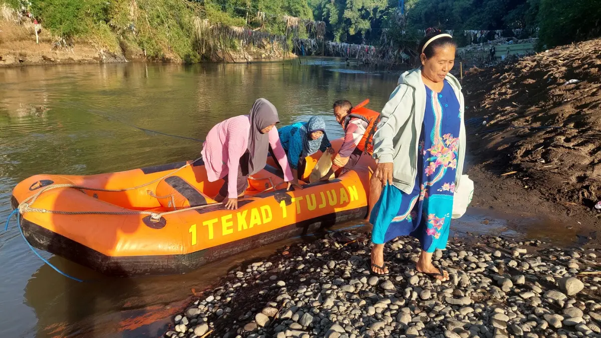 SATU TEKAD: Sejumlah ibu-ibu yang bekerja sebagai asisten rumah tangga menyeberang Sungai Bedadung menggunakan perahu karet untuk berangkat kerja, kemarin (21/4). (JUMAI/RADAR JEMBER)