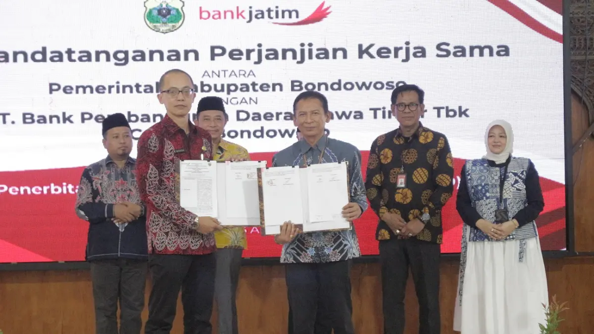 KOLABORASI: Pemimpin Cabang PT Bank Pembangunan Daerah Jawa Timur Bondowoso, Heru Widodo bersama Pemerintah Kabupaten Bondowoso menunjukkan perjanjian kerjasama tentang penerbitan kartu kredit pemerintah daerah.