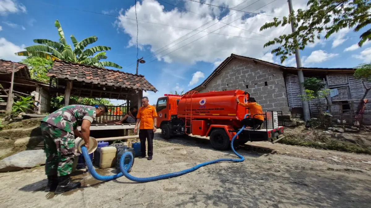 DISTRIBUSI TERUS: Petugas BPBD Bondowoso mengisi air bersih di wadah yang disiapkan oleh warga terdampak kekeringan.