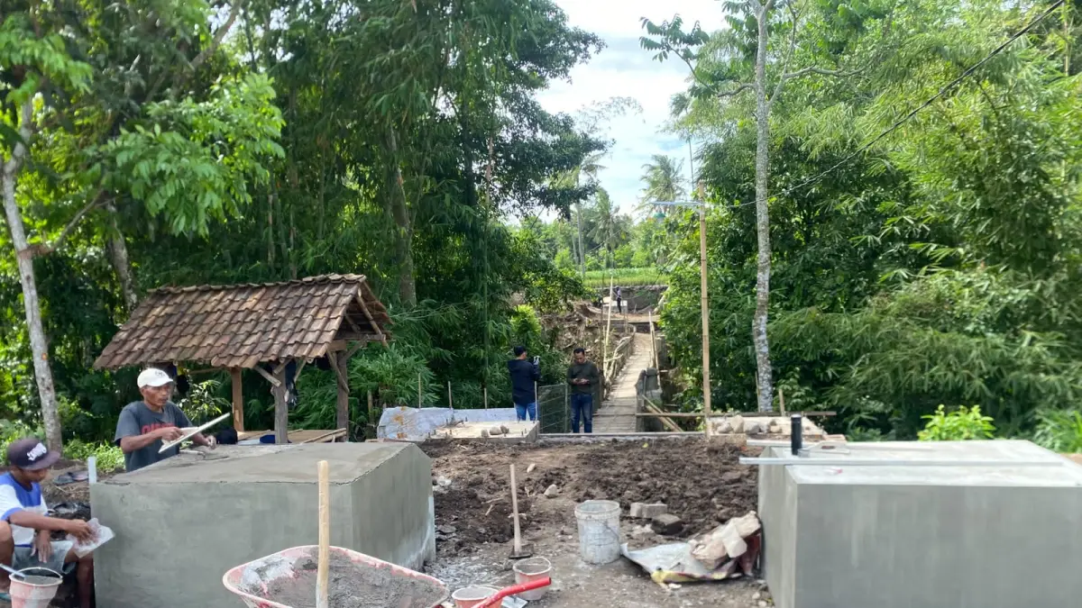 BERHATI-HATI: Salah seorang warga menyeberang jembatan yang menghubungkan Desa Sukowiryo dan Desa Kejawan, saat ini jembatan tersebut tengah diperbaiki.(ILHAM WAHYUDI/RADAR IJEN)