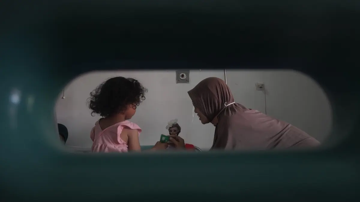 MASIH DIRAWAT: Hasna Wulandari (kanan) orang tua Kirani Sabita Putri Marwah mengajak anaknya bermain di tengah perawatan seusai menyantap menu MBG yang menyebabkan diare dan muntah di Puskesmas Kaliwates, kemarin (21/5). (SIDKIN ALI/RADAR JEMBER)