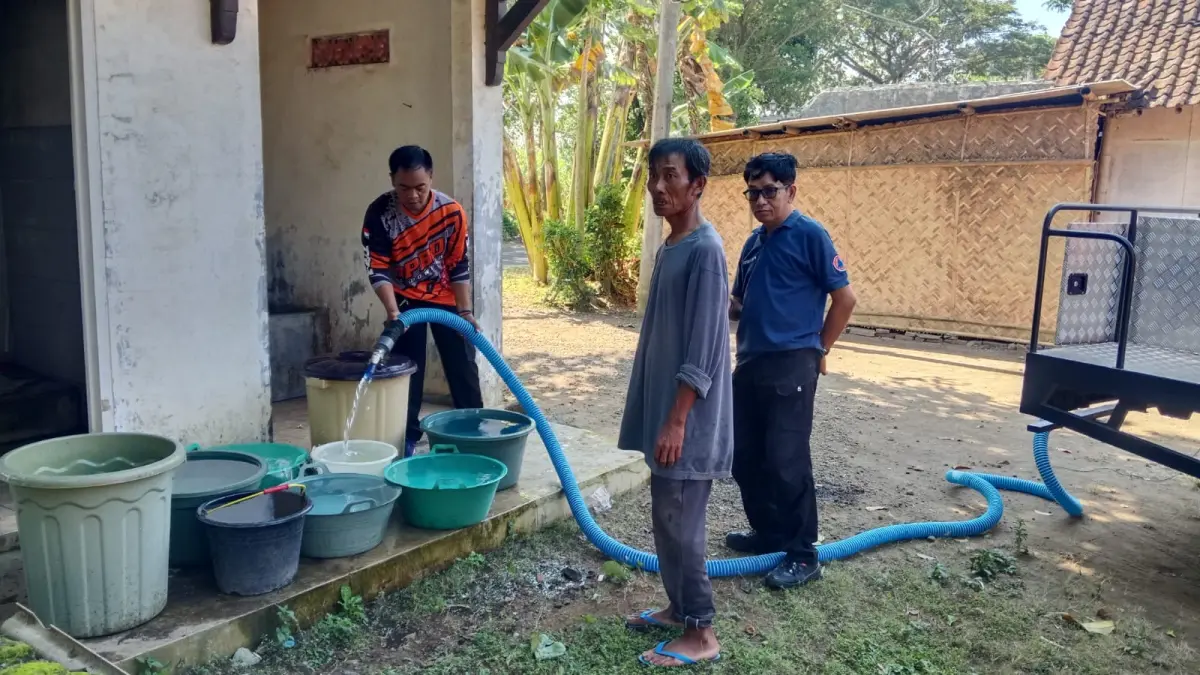 MENGANTRE: Sejumlah Petugas BPBD Bondowoso mengisi wadah air bersih yang sudah disiapkan oleh warga sebelumnya.(ILHAM WAHYUDI/RADAR IJEN)