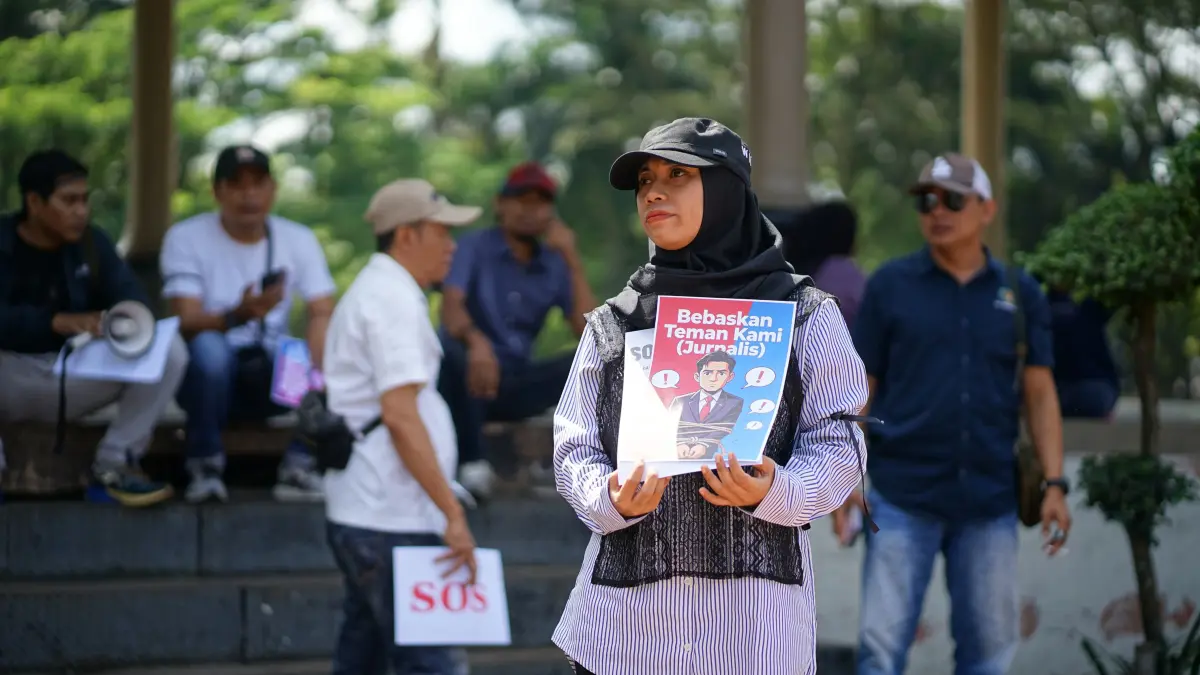 SOLIDARITAS: Ketua PWI Bondowoso membentangkan poster tuntutan dari aksi damai yang mereka gelar di Monumen Gerbong Maut, kemarin. (ILHAM WAHYUDI/RADAR IJEN)

