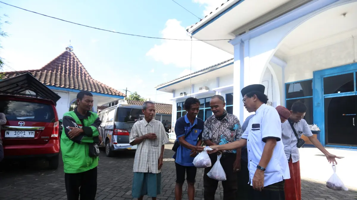 SELALU DIINGAT: Direktur Jawa Pos Radar Jember Abdul Choliq Baya (kanan) menyerahkan daging kurban kepada para loper koran di halaman kantor, Jumat (29/5). (YULIO FA/RADAR JEMBER)